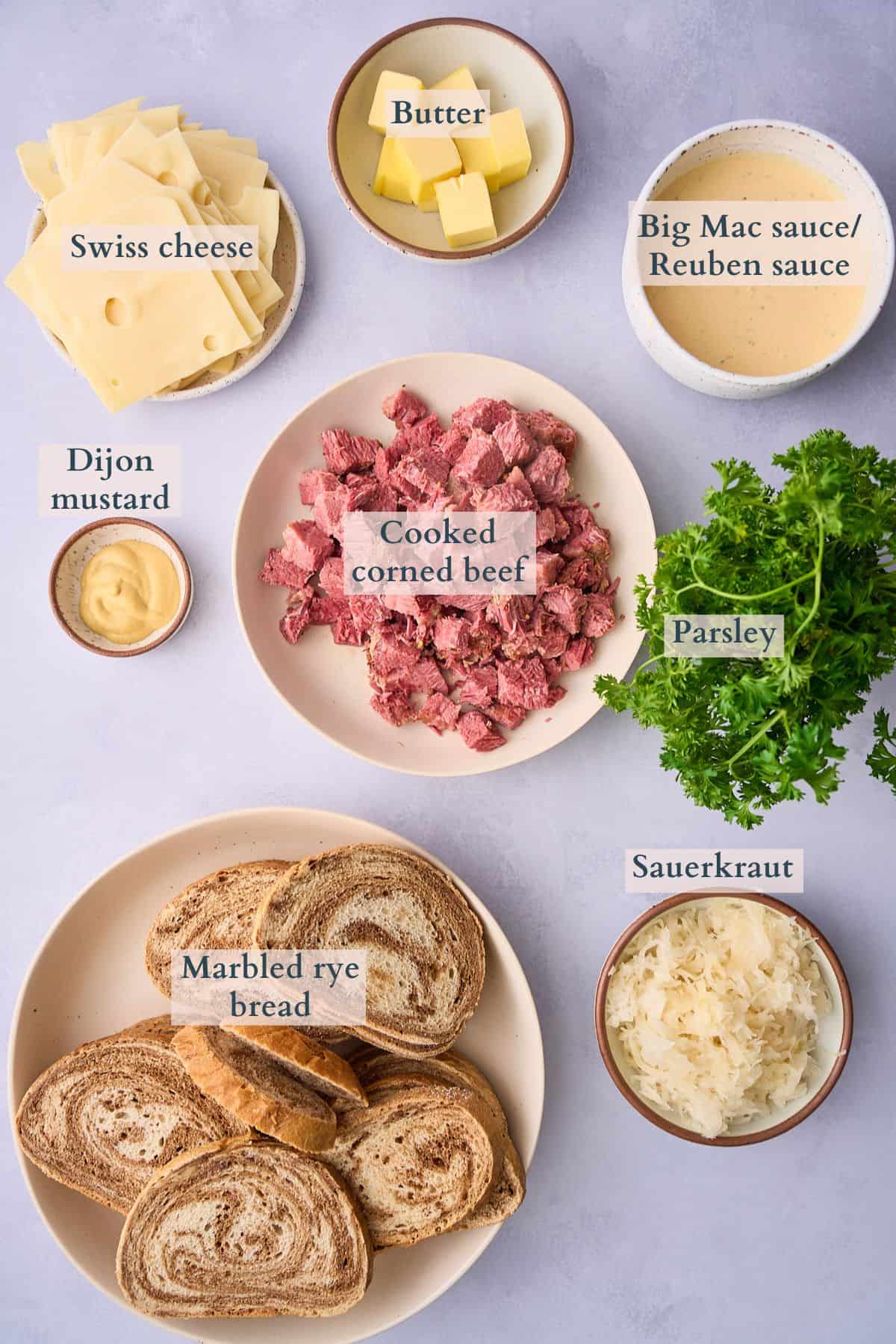 Ingredients to make a reuben casserole laid out on a table and labeled to denote each ingredient. 