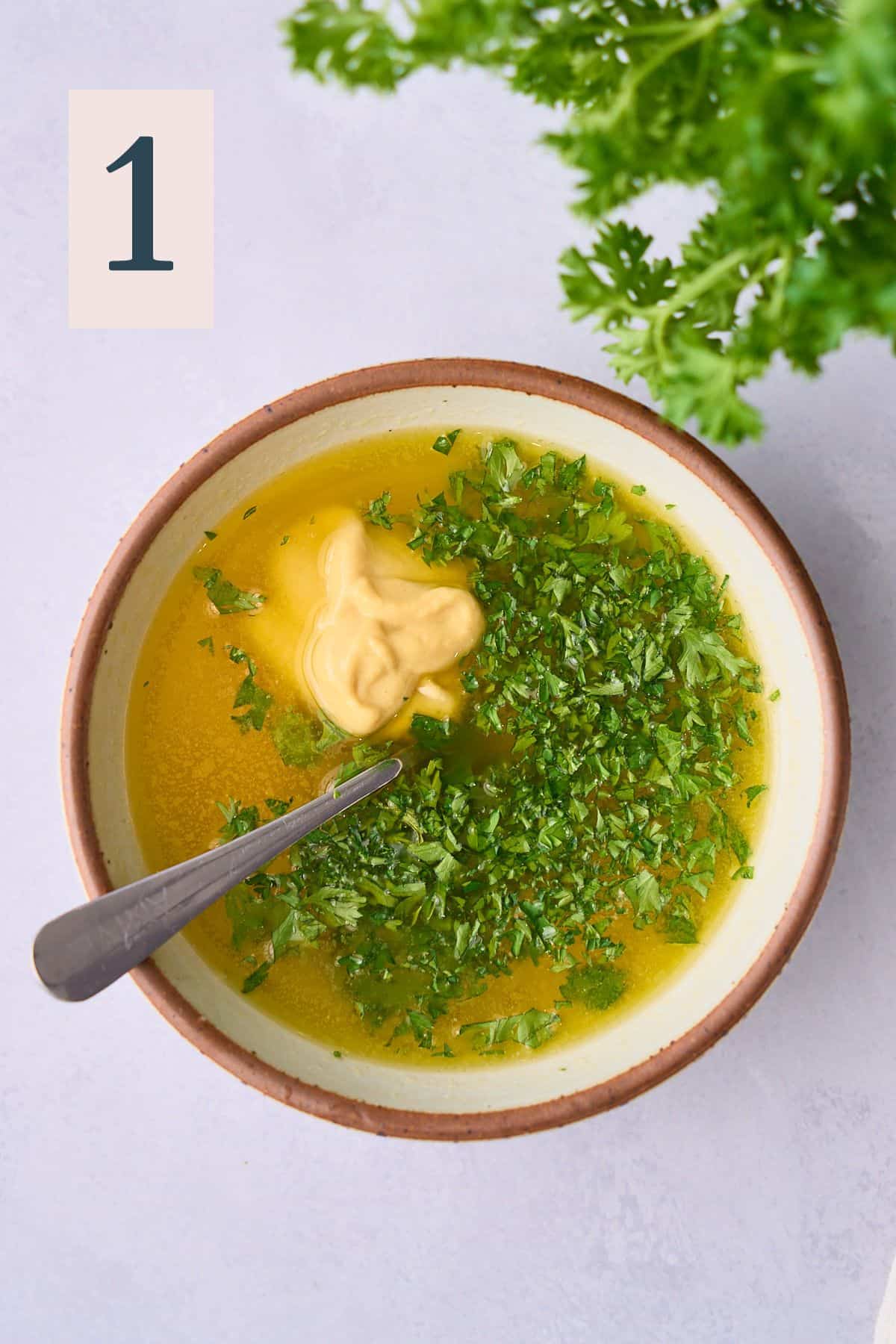 Melted butter in a bowl with fresh parsley and Dijon mustard. 