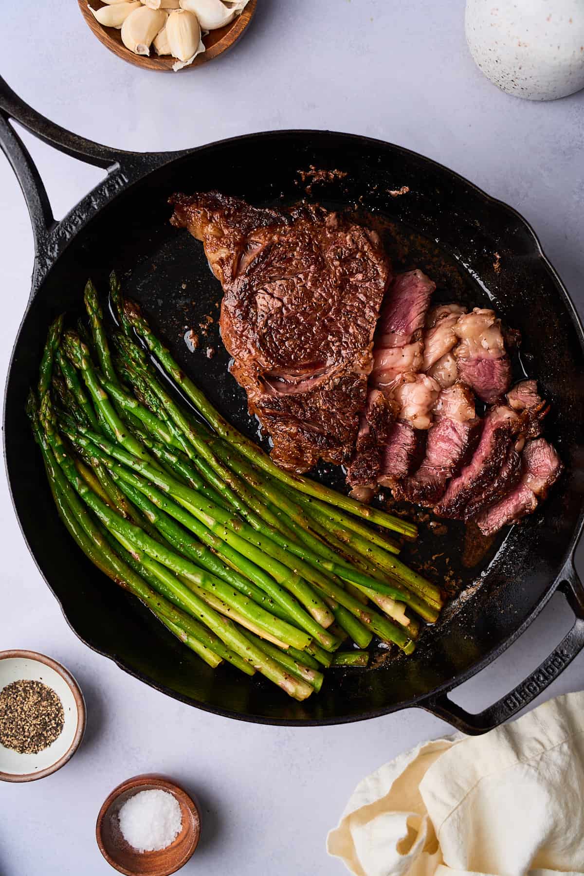 Ribeye steak and asparagus cooked in a cast iron skillet and cut into to reveal the center cooked a perfect medium rare.