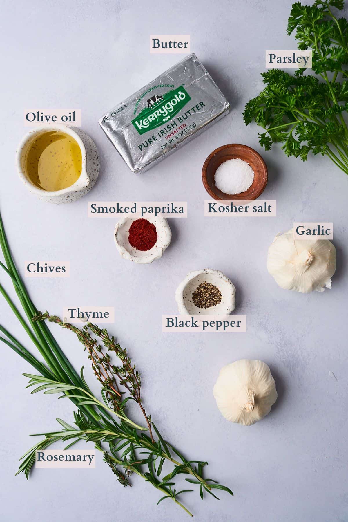 Ingredients to make roasted garlic butter laid out on a table and labeled to denote each ingredient.