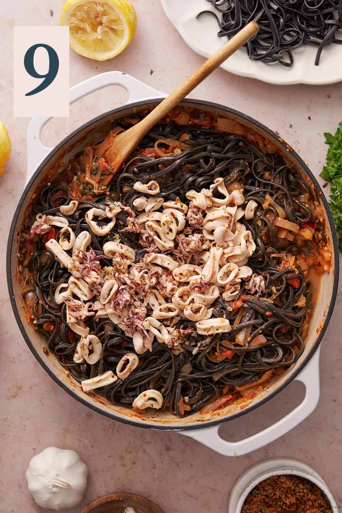 black pasta with squid in a skillet with a fresh tomato sauce.