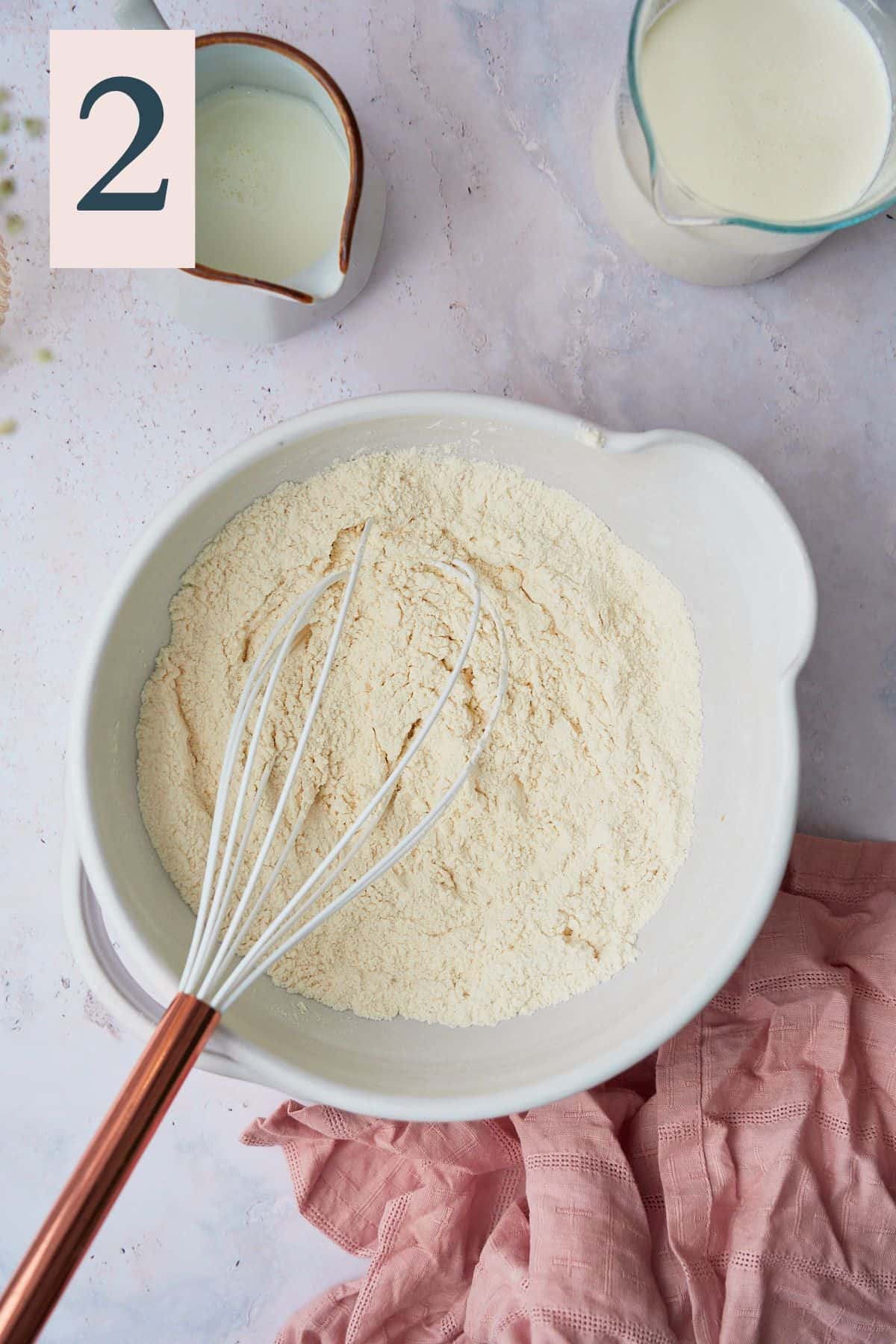 Dry ingredients to make pancakes mixed together in a bowl with a whisk. 