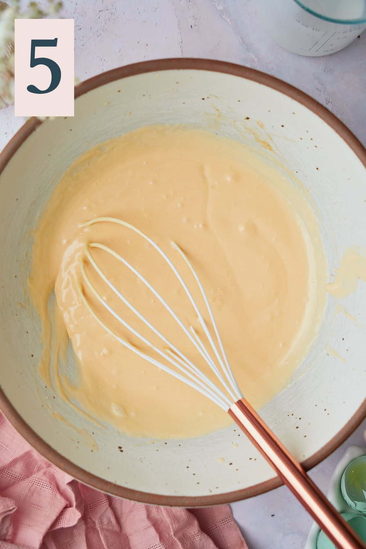 Creamy mixture in a large mixing bowl with a whisk. 