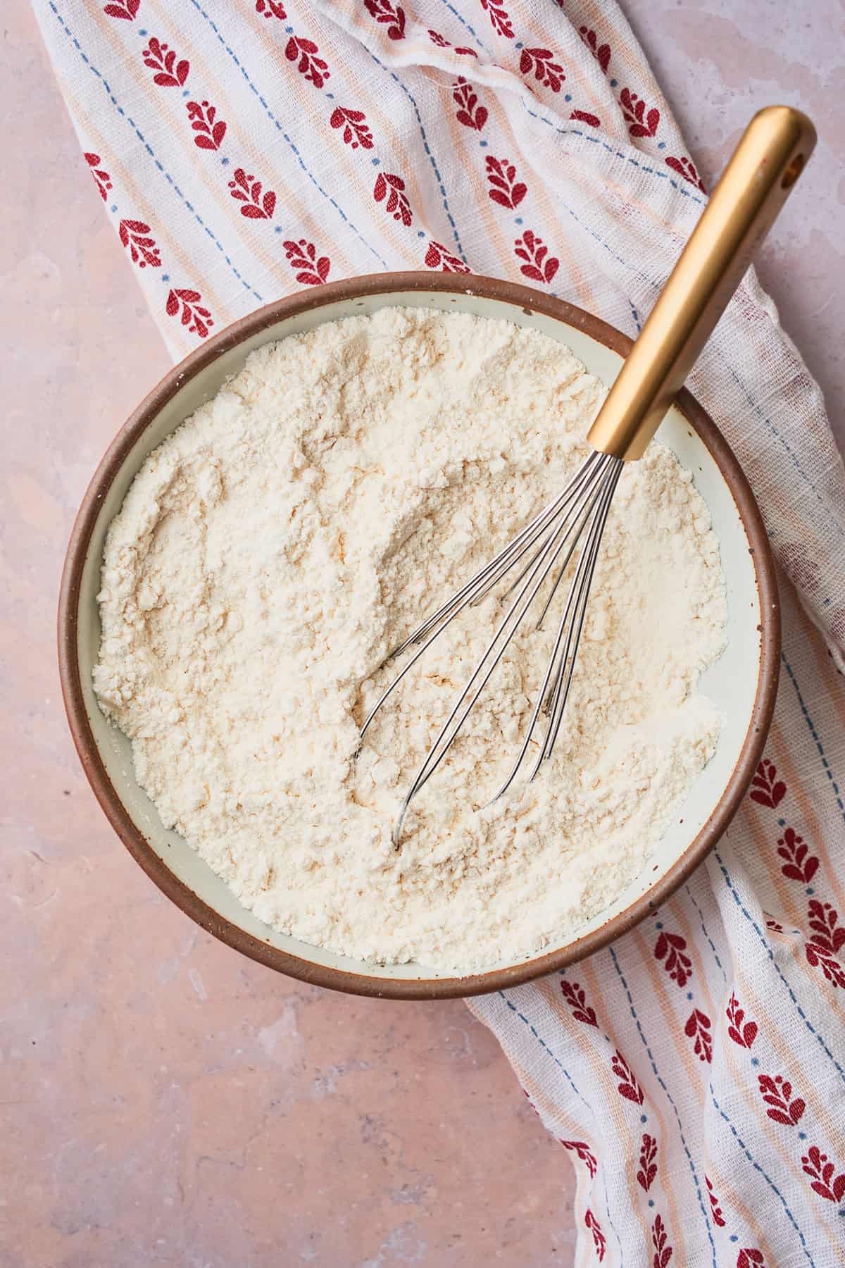 Flour and salt being mixed together in a bowl with a whisk. 