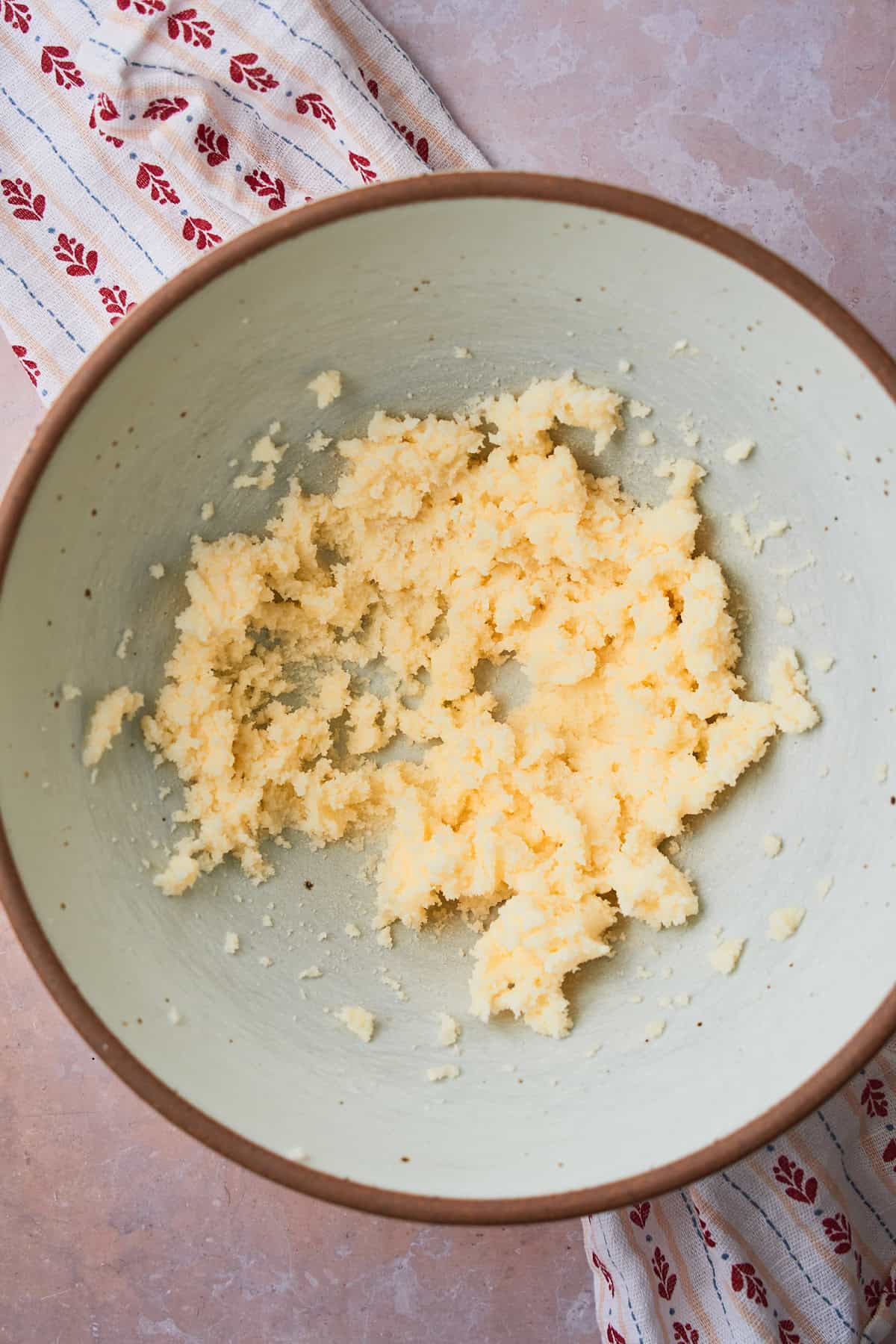 Butter and sugar creamed together in a bowl with a printed linen napkin underneath. 