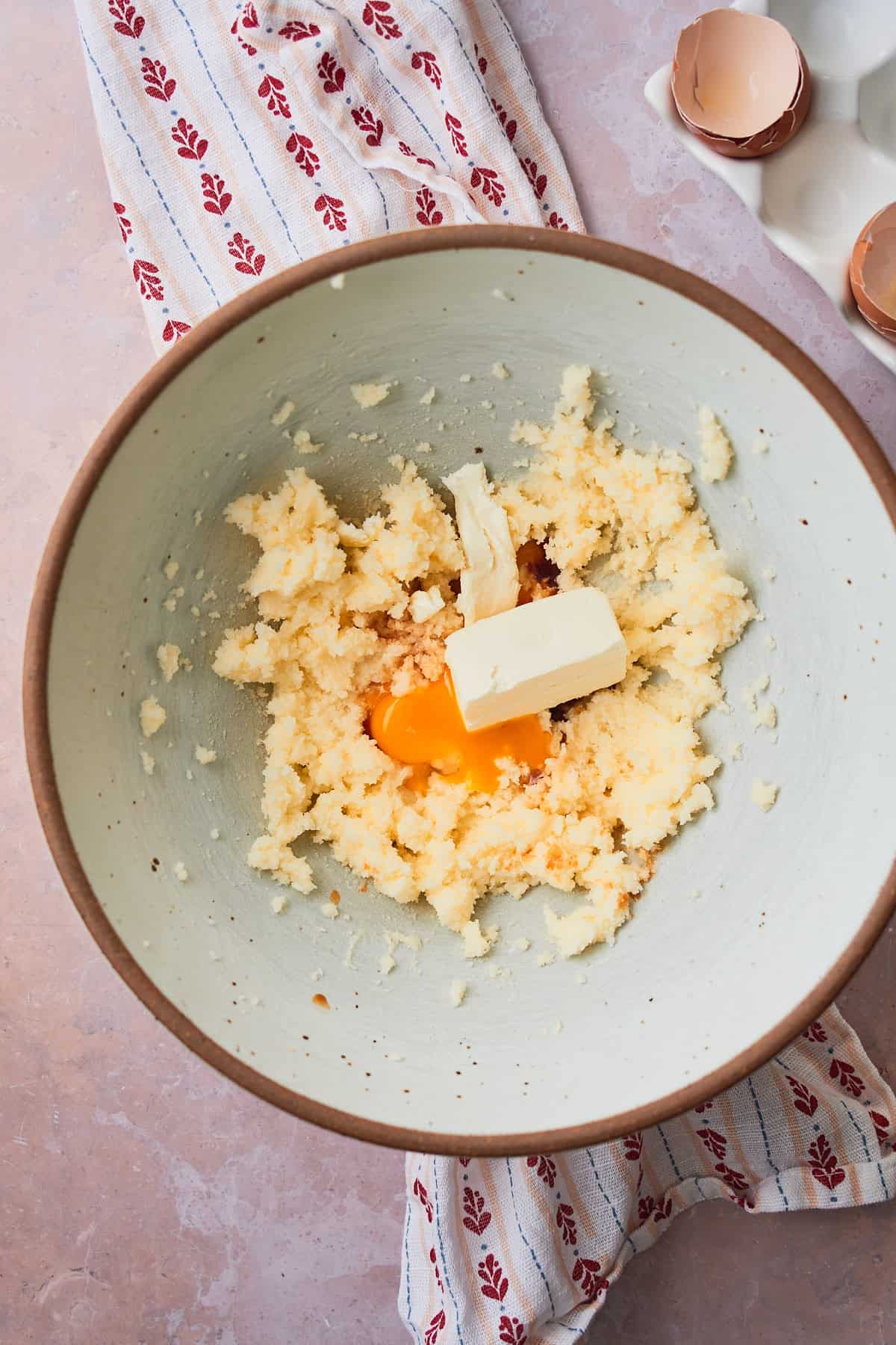 Cream cheese, egg yolks, and vanilla extract added to a butter and sugar mixture in a large bowl. 