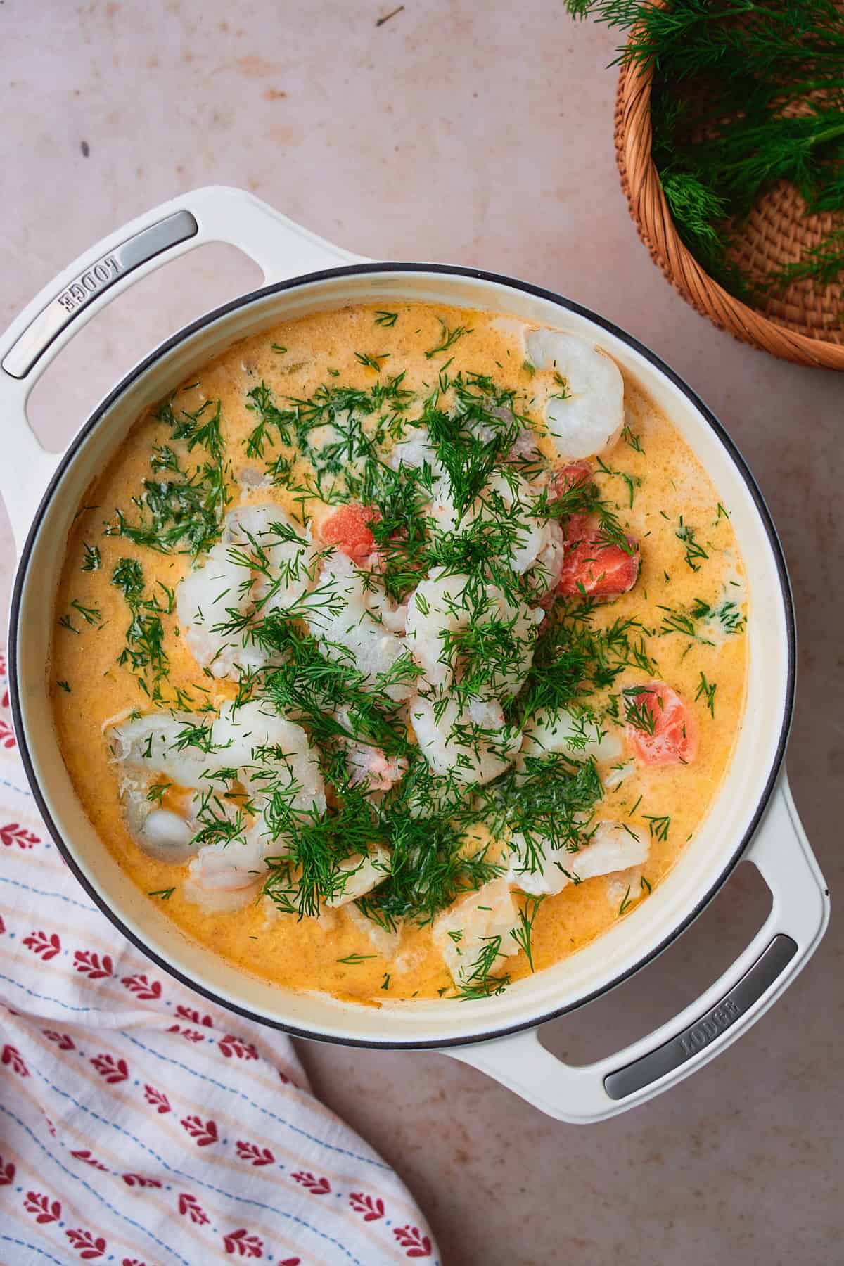 Cream added to a pot with fresh shrimp, salmon, cod, and dill to make a creamy fish soup.