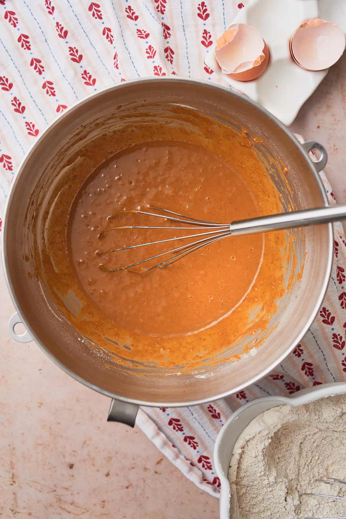 Flour added to a wet mixture making molasses and rye rolls in a mixing bowl to form a paste. 