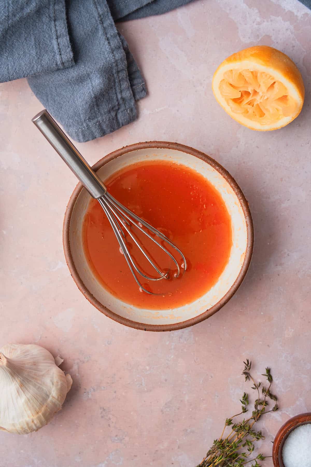 Hot sauce, lemon juice, and honey being whisked in a small container. 