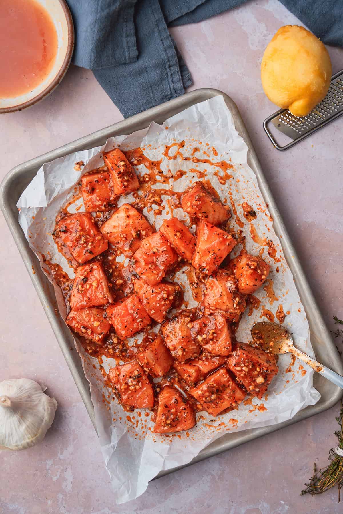 Salmon pieces coated in a glossy glaze on a parchment lined baking sheet. 