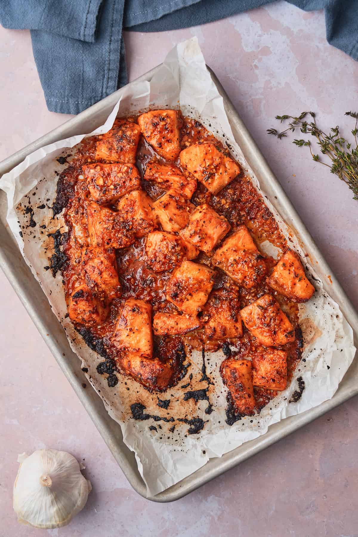 Baked salmon pieces with browned edges on a  parchment lined baking sheet.