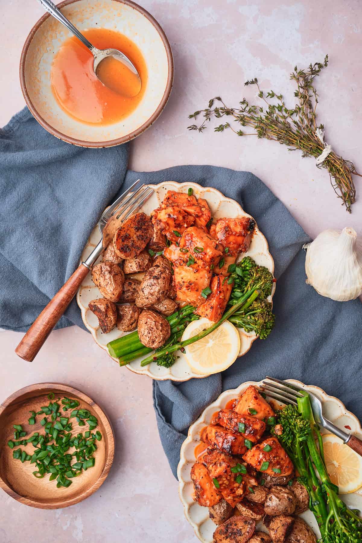 Salmon bites with glaze in bowl on a ruffled ceramic plate and dark blue napkin nearby.