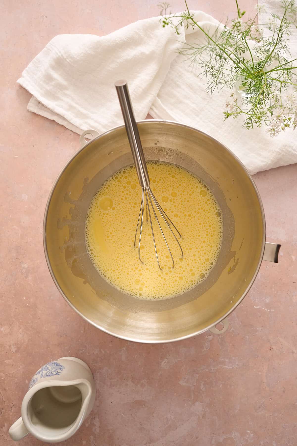 Whisking egg, milk, and butter mixture in a metal mixing bowl.