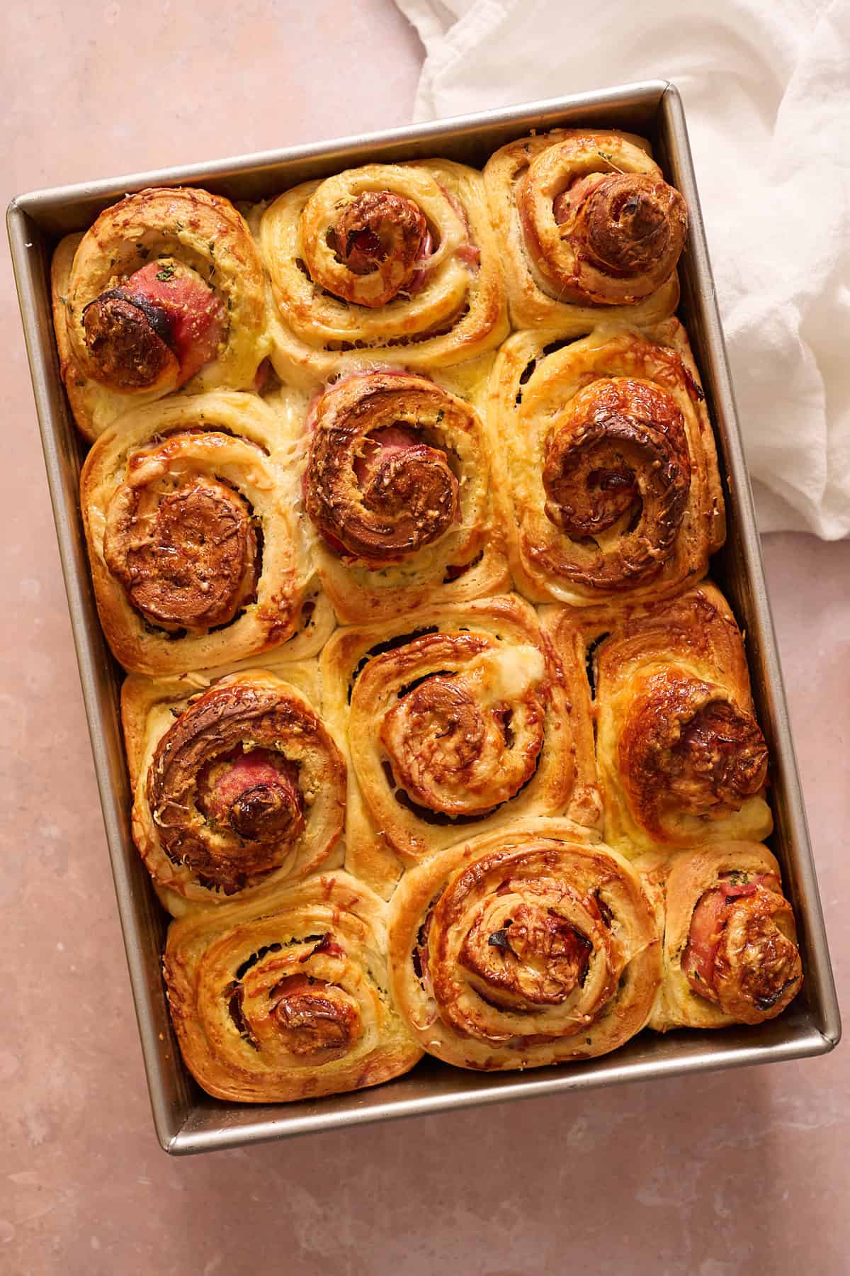 Baked golden brown ham and cheese rolls in a metal pan. 
