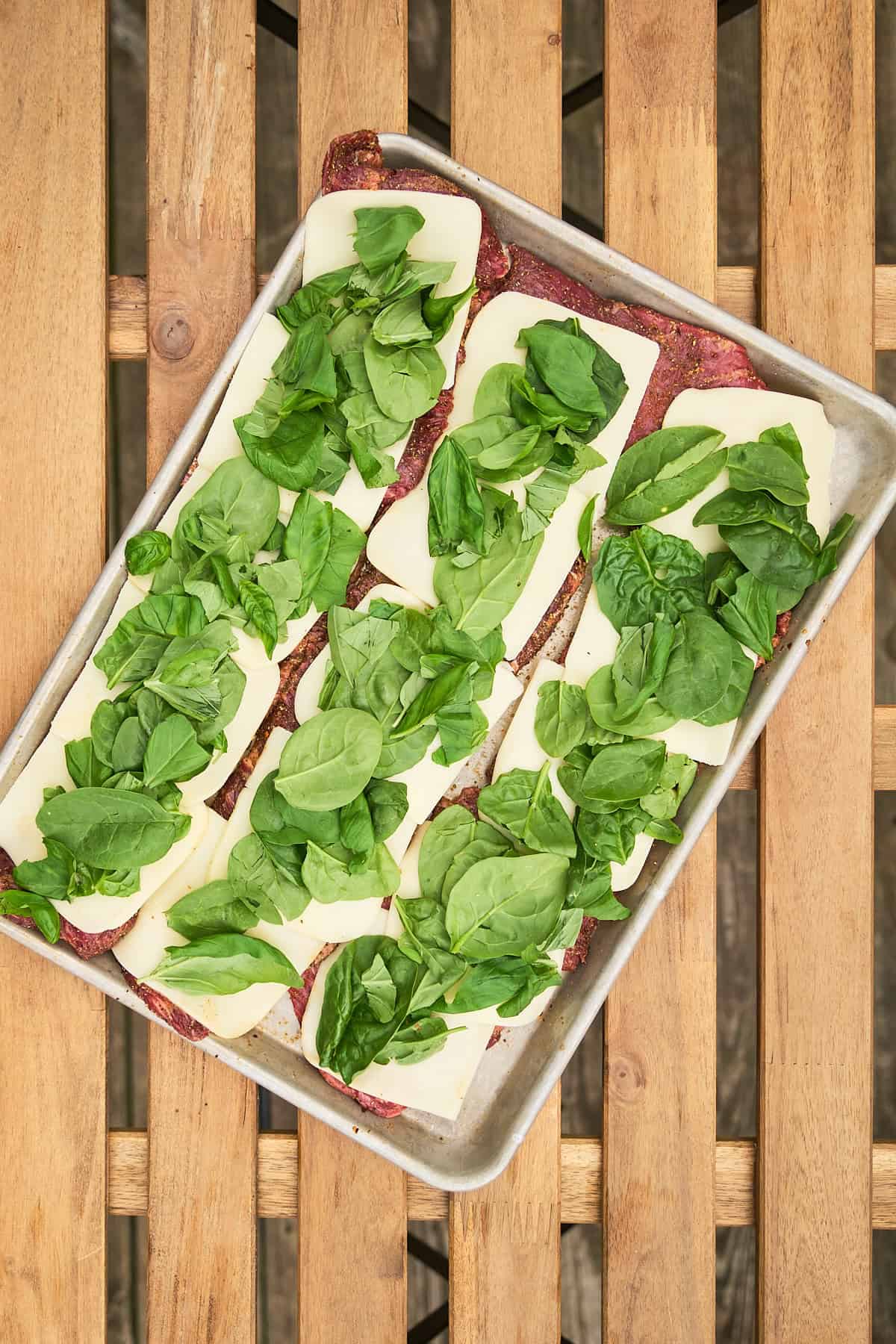 Steaks covered with provolone cheese slices, basil, and spinach.
