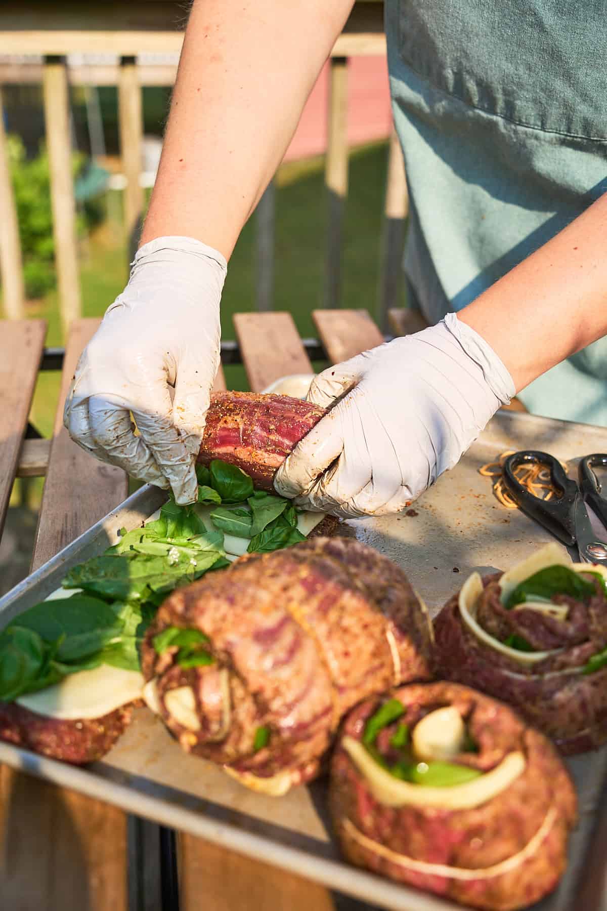 Hands tightly rolling skirt steaks filled with spinach and cheese.