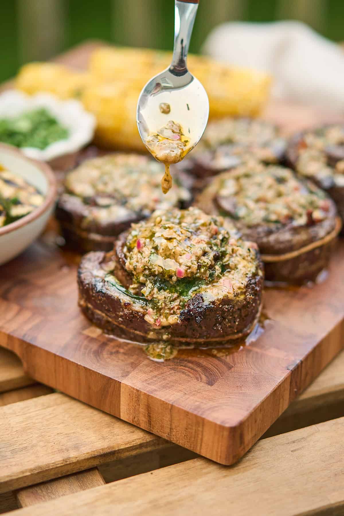 Spoon drizzling steak pinwheels with a buttery herbed dipping sauce.