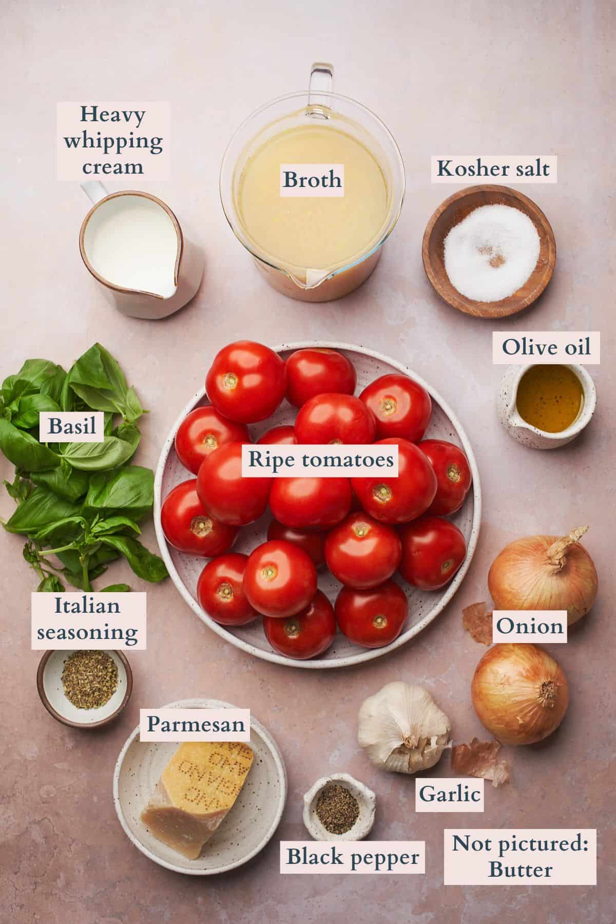 Ingredients to make a creamy roasted tomato soup laid out on a table and labeled to denote each ingredient.