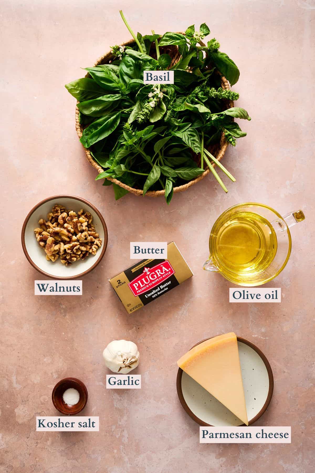 Pesto butter ingredients laid out on a table and labeled to denote each ingredient.