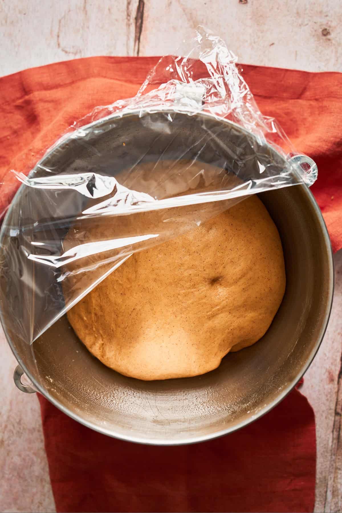 Cinnamon roll dough that has risen to become nice and puffy in a bowl.