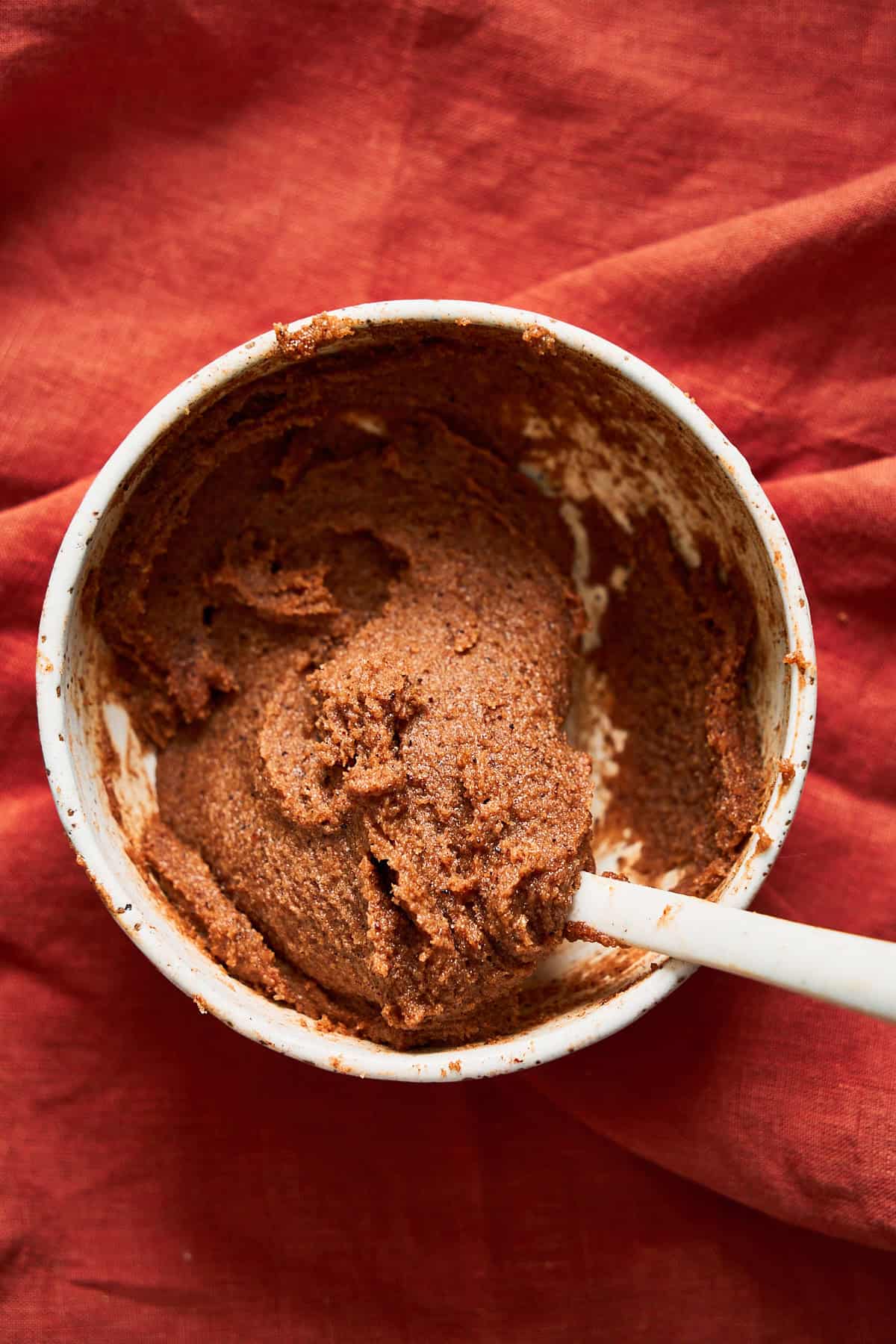 Brown sugar filling mixture for cinnamon rolls in a bowl on top of a terra cotta colored linen.