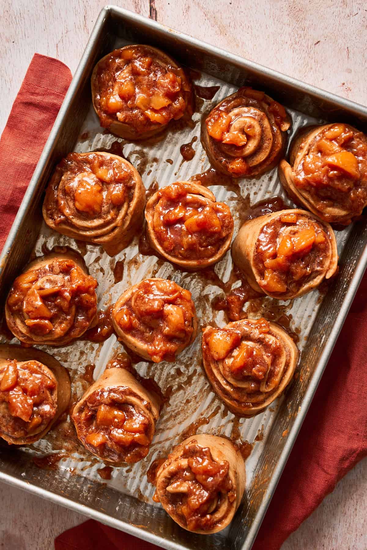 Peach cinnamon roll pieces cut and placed into a greased baking sheet getting ready for the second rise.