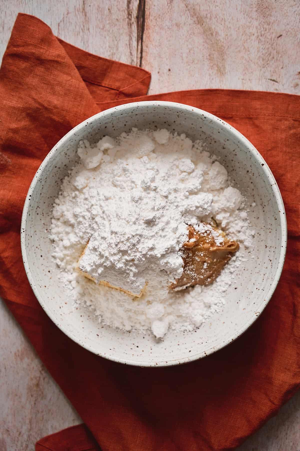 Powdered sugar, cream cheese, and butter in a mixing bowl to make frosting.