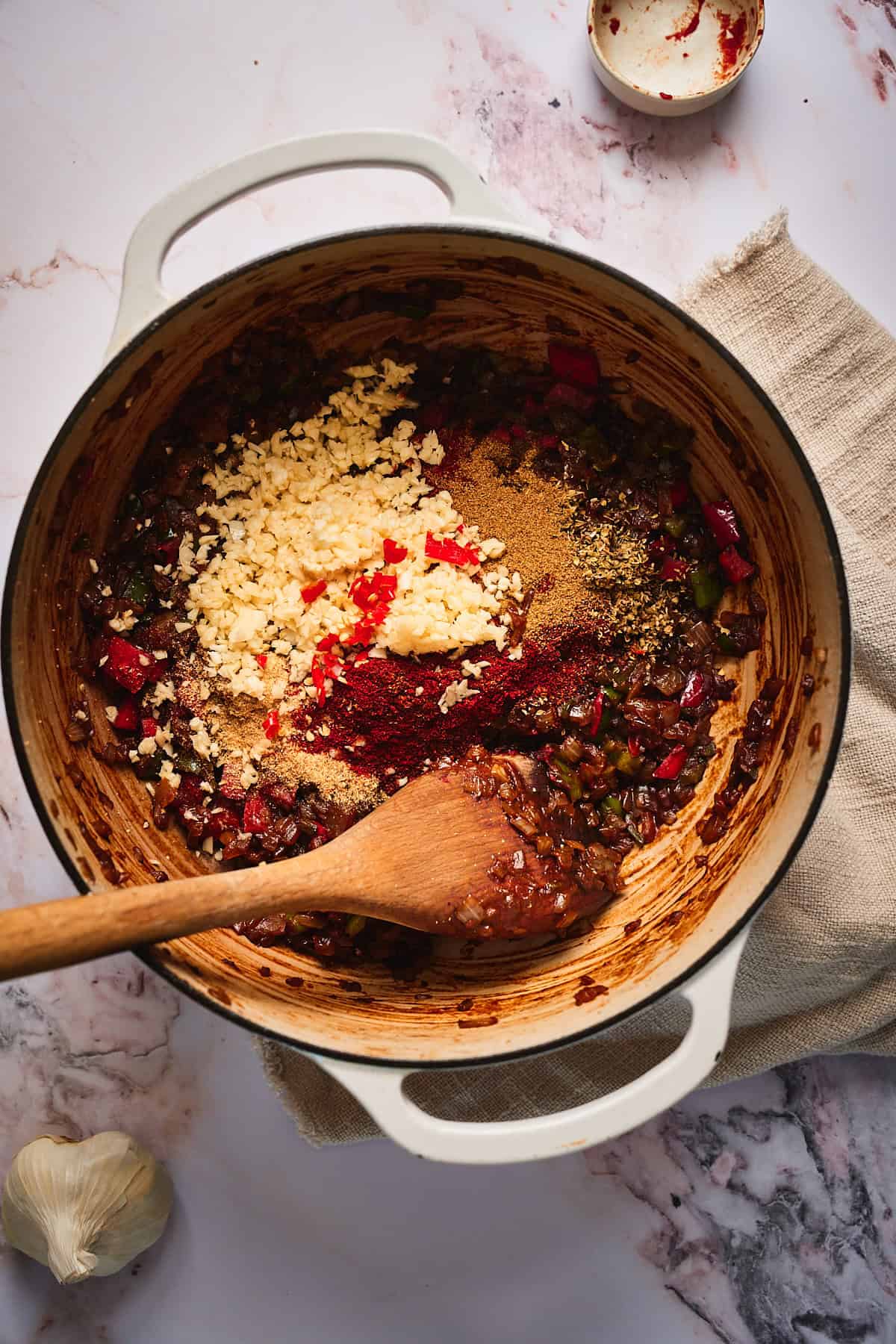 Vegetables cooking in a large Dutch oven with seasonings and lots of garlic added.