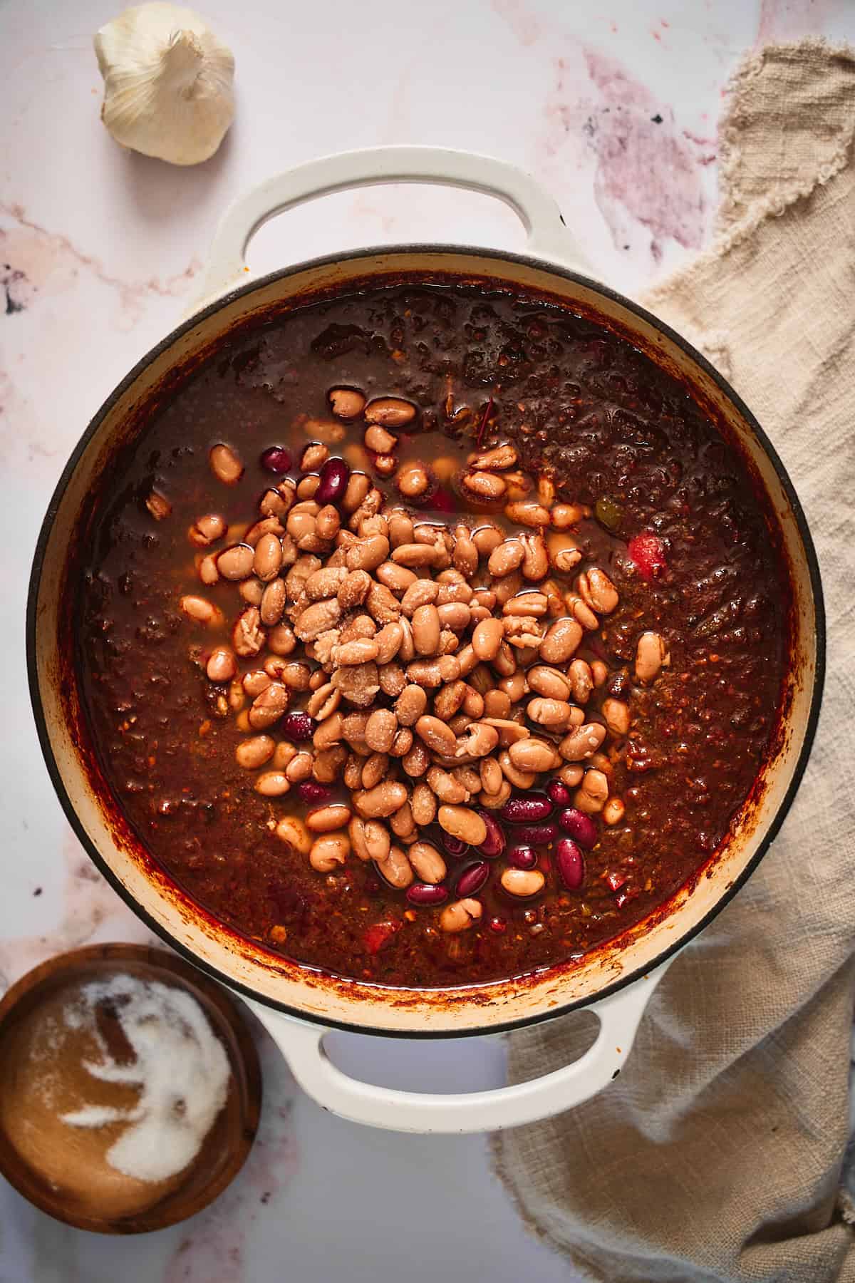 Kidney and pinto beans added with lots of salt to a pot of chili.