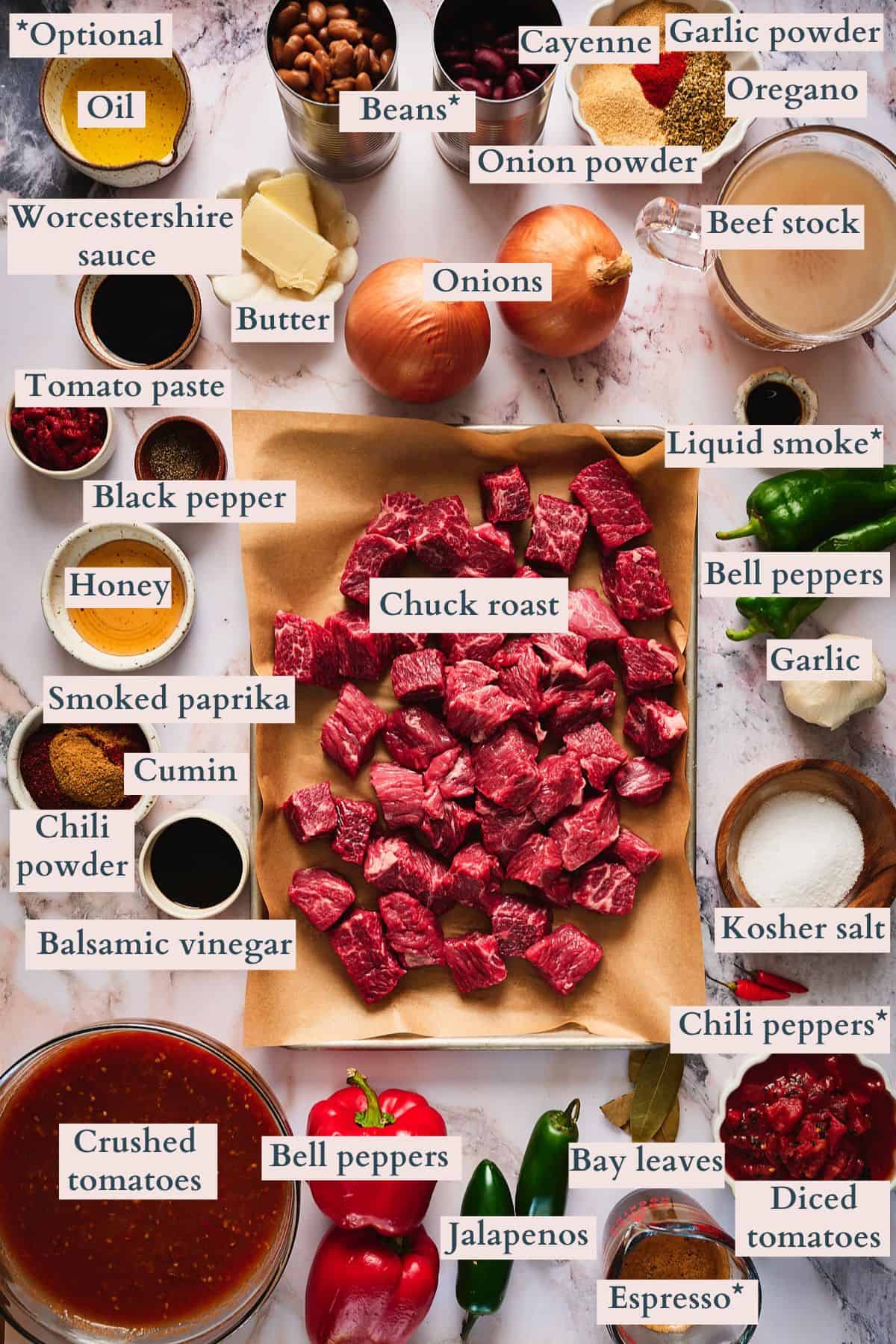 Ingredients to make chuck roast chili laid out on a table and labeled to denote each ingredient.