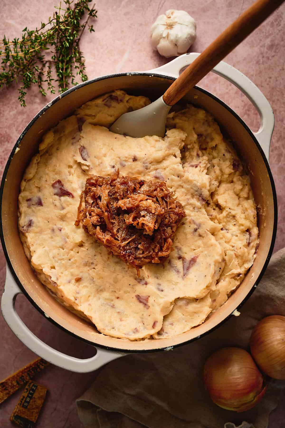 Stirring caramelized onions into a large pot of creamy mashed potatoes. 