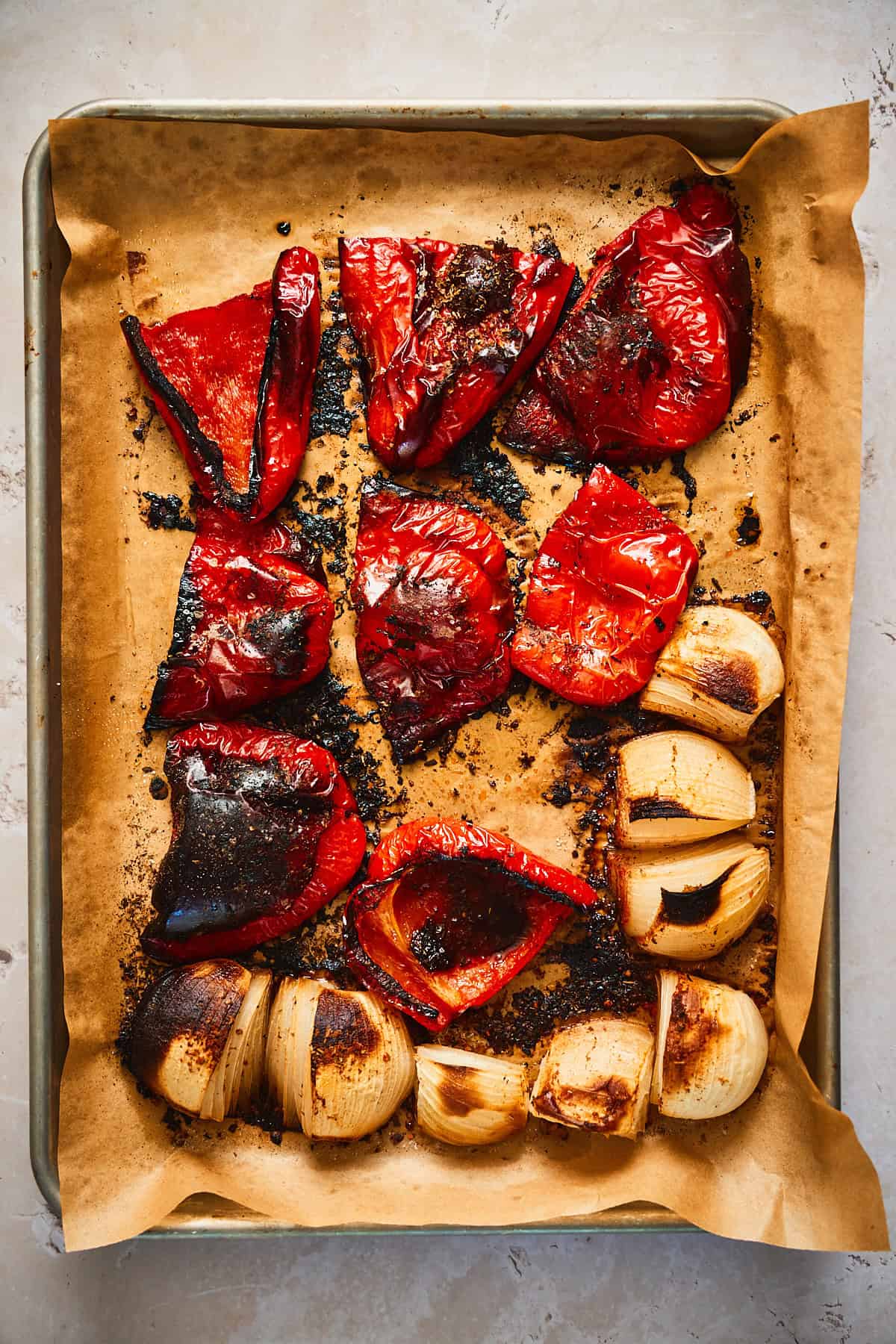 Roasted and very charred tomatoes on a sheet pan.