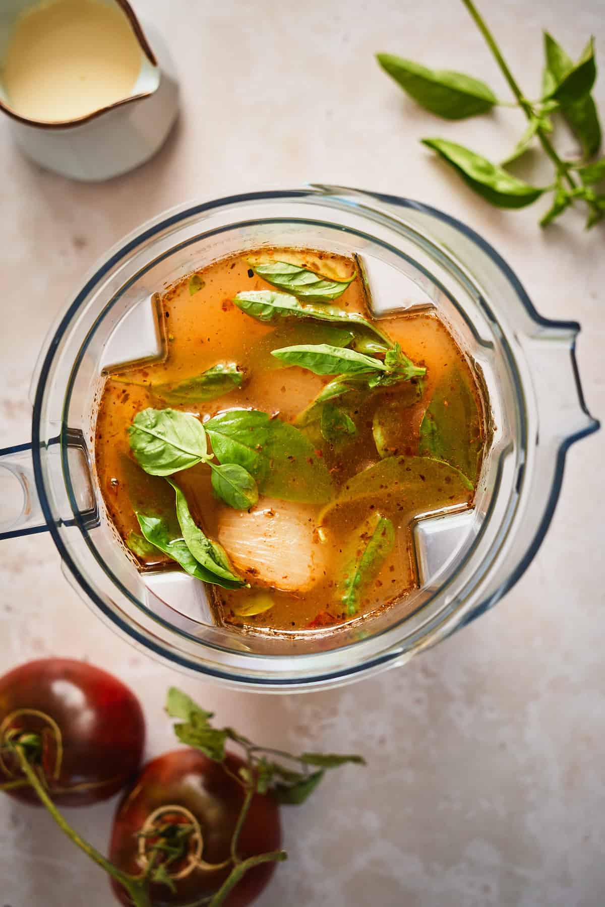 Broth, basil, and veggies added to a blender to make soup. 