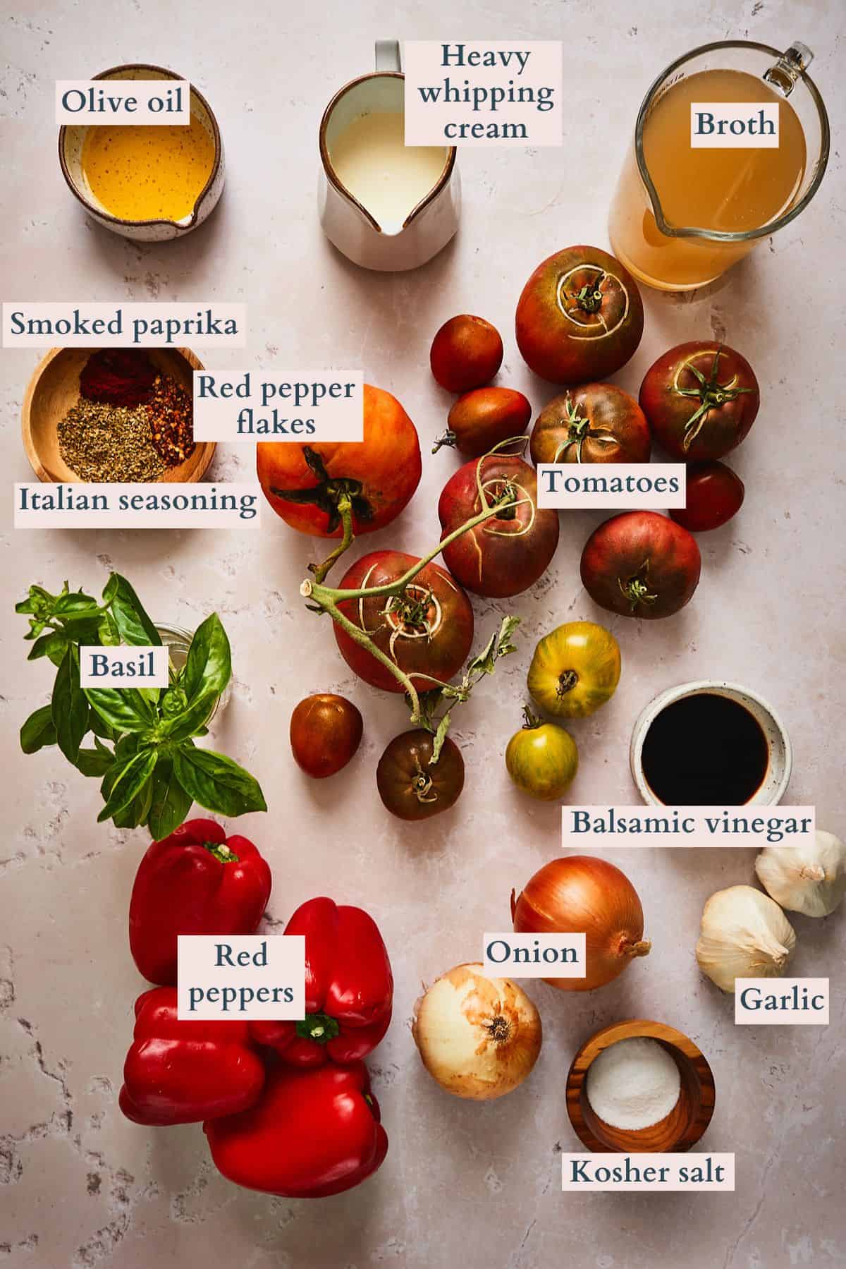 Ingredients to make roasted red pepper tomato soup laid out on a table and labeled to denote each ingredient.