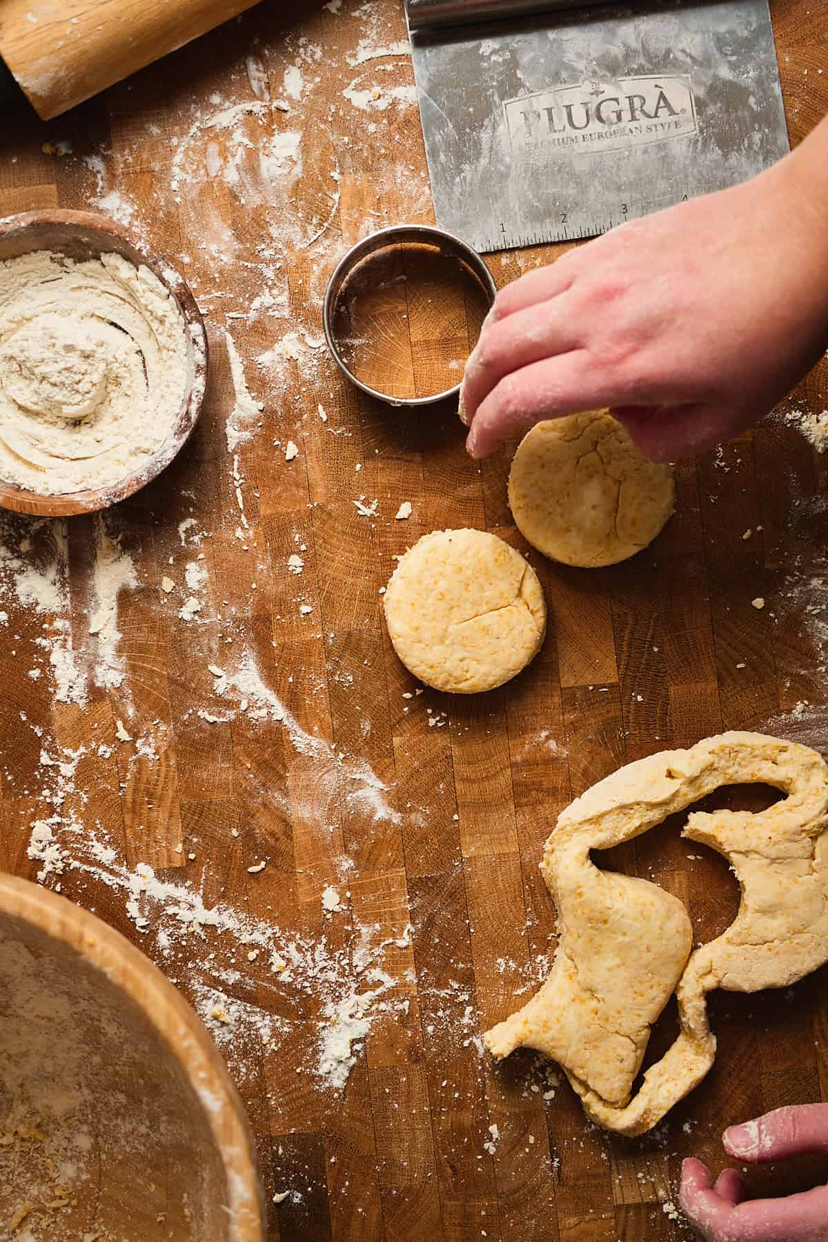 Buttery cornbread biscuits on a wooden surface with baking ingredients and utensils.