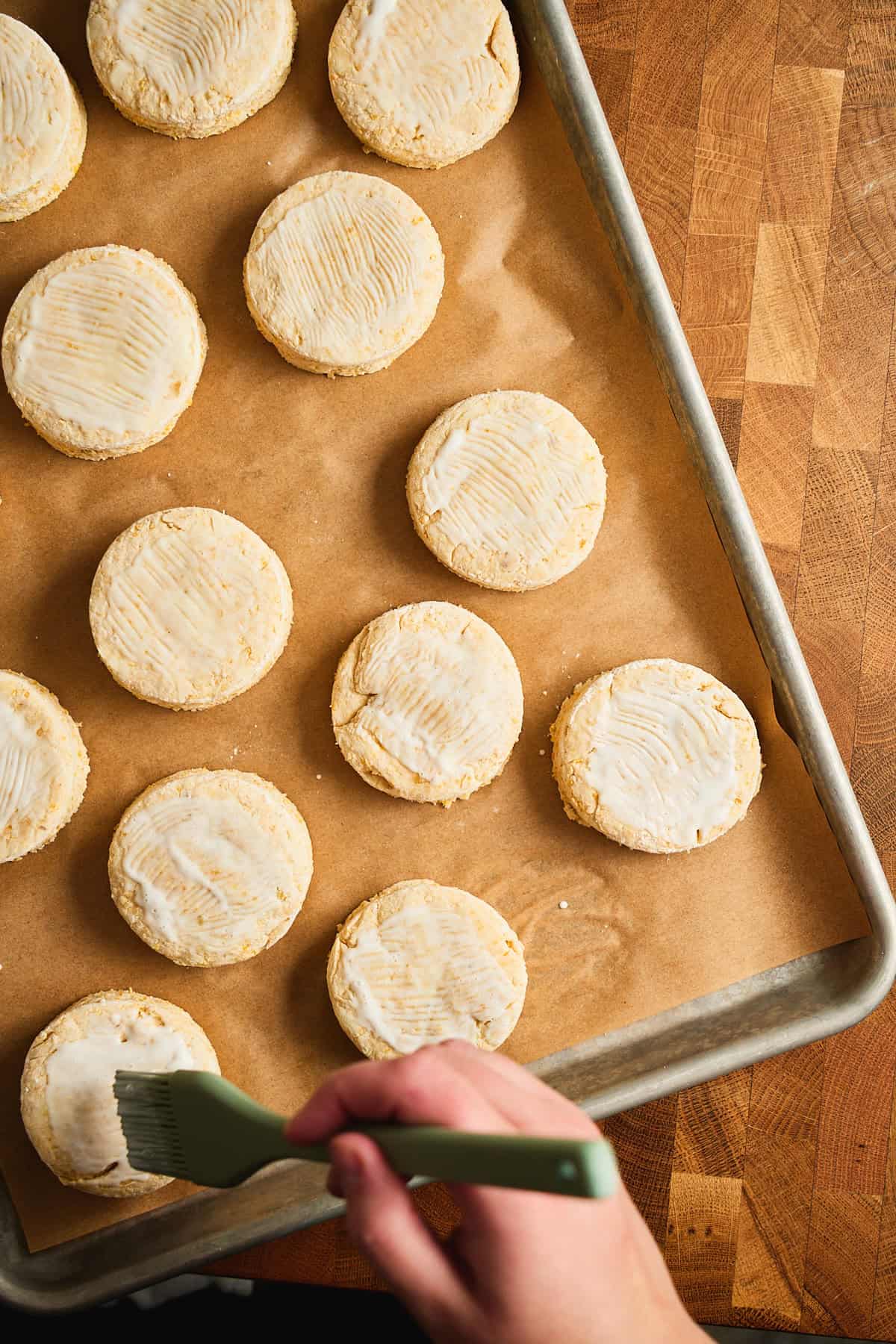 Biscuits on a baking sheet with a brushed with buttermilk before baking.