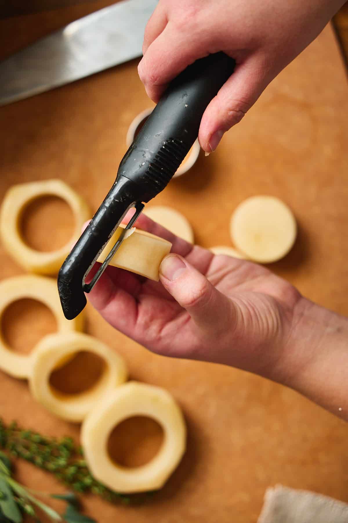 Hand peeling off any excess or unsmooth bits of potato from the edges of fondant potatoes to get a really clean, uniform edge.