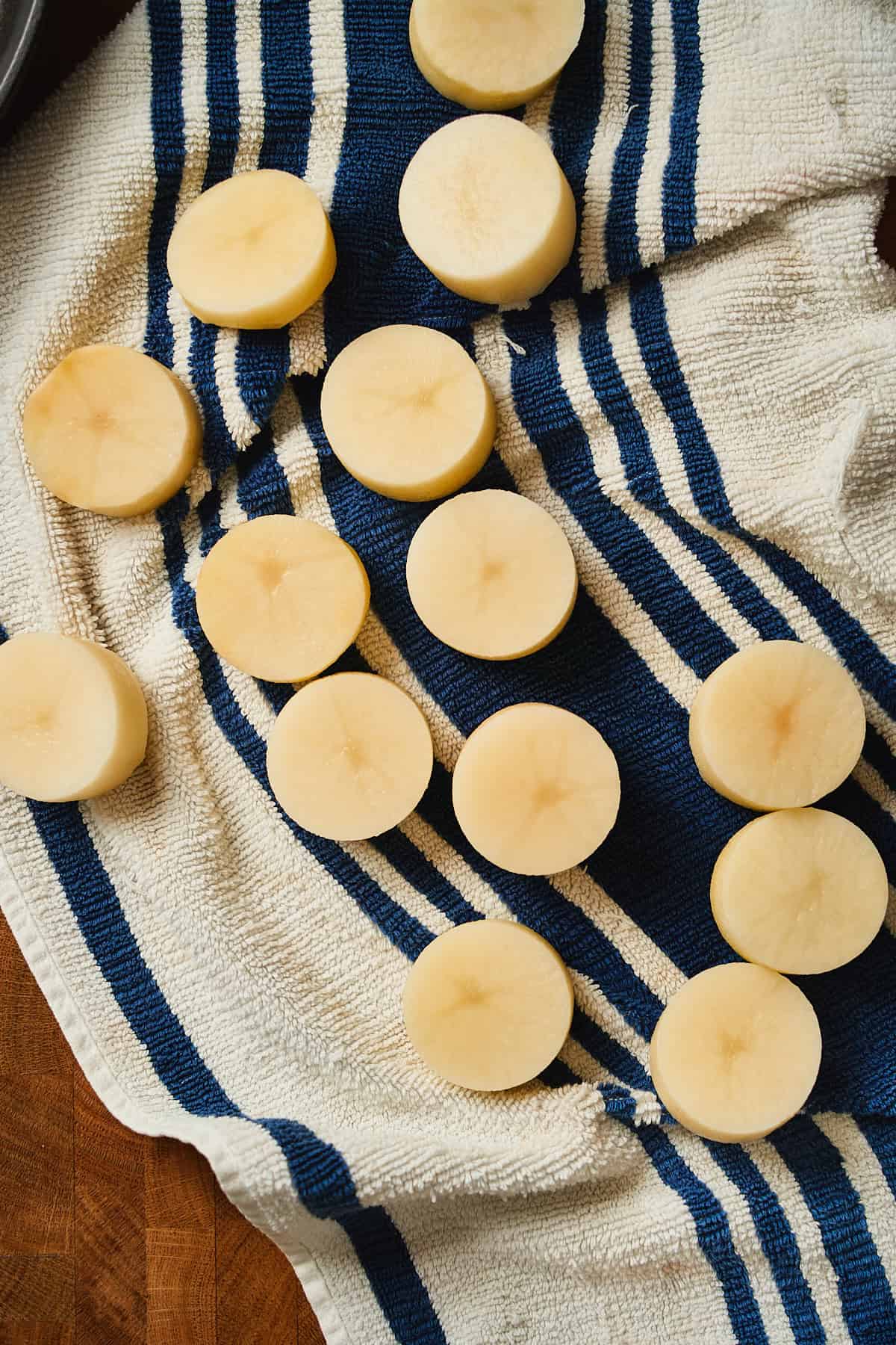 Potato rounds on a kitchen towel being dried off after sitting in cold water.