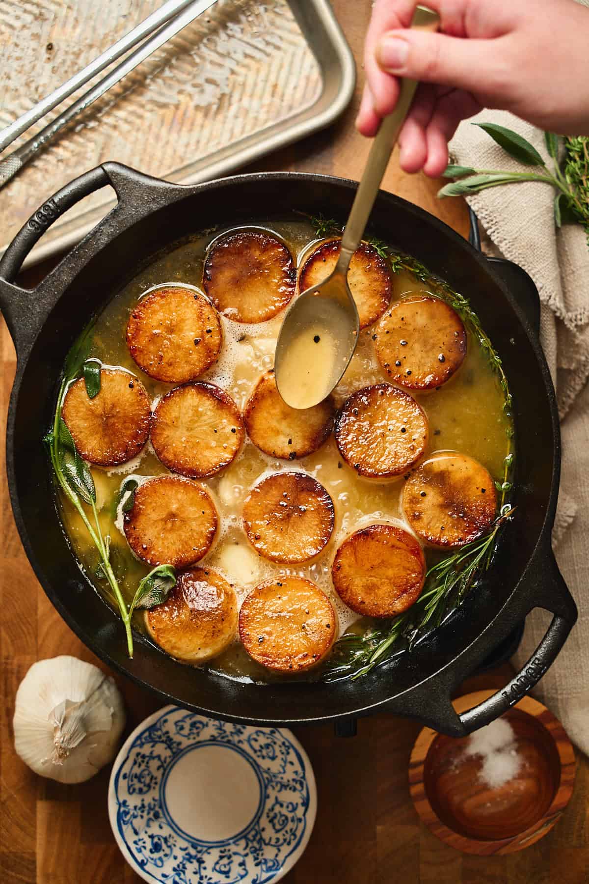 Hand basting the tops of the potatoes with the melted butter, with the herbs and garlic infusing into the butter.