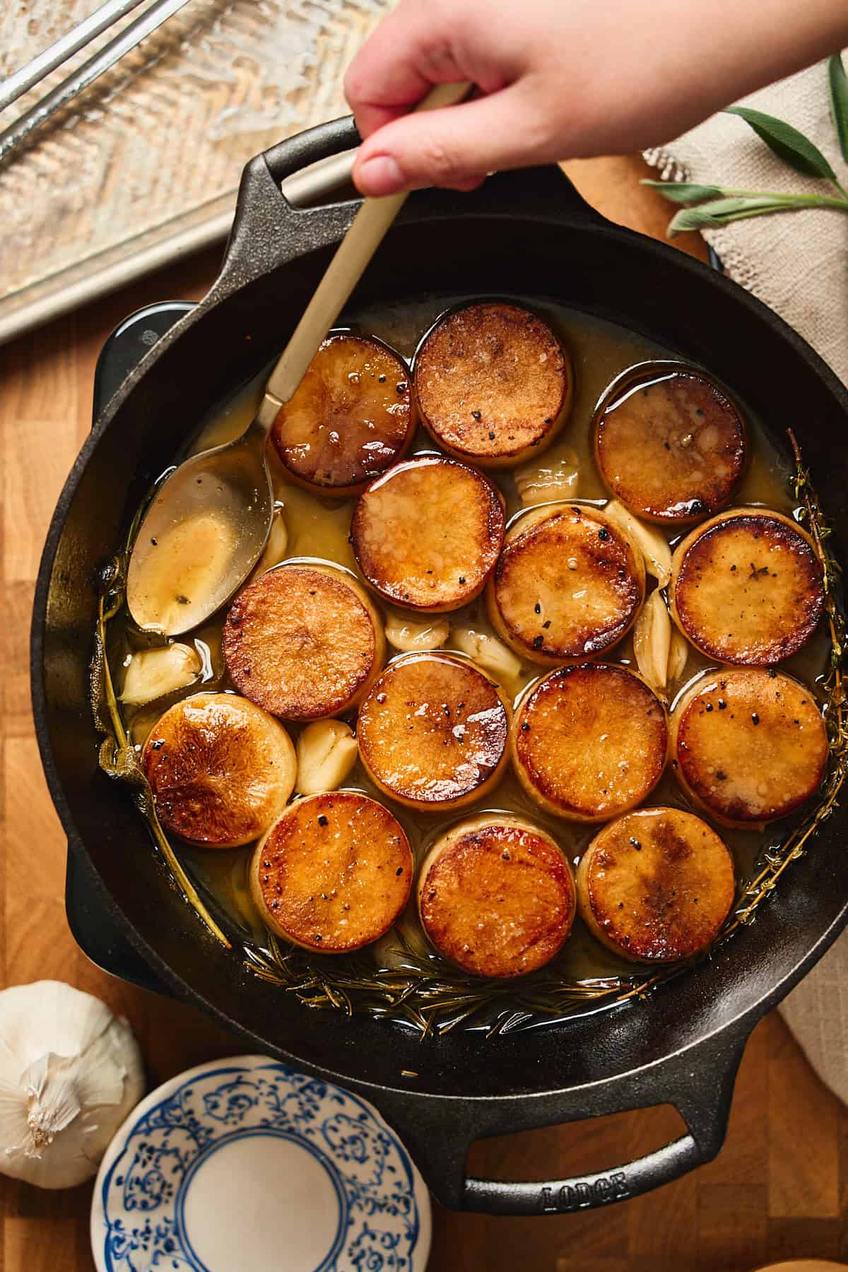 Golden roasted potatoes in cast iron skillet with garlic and herbs and a buttery pan sauce.