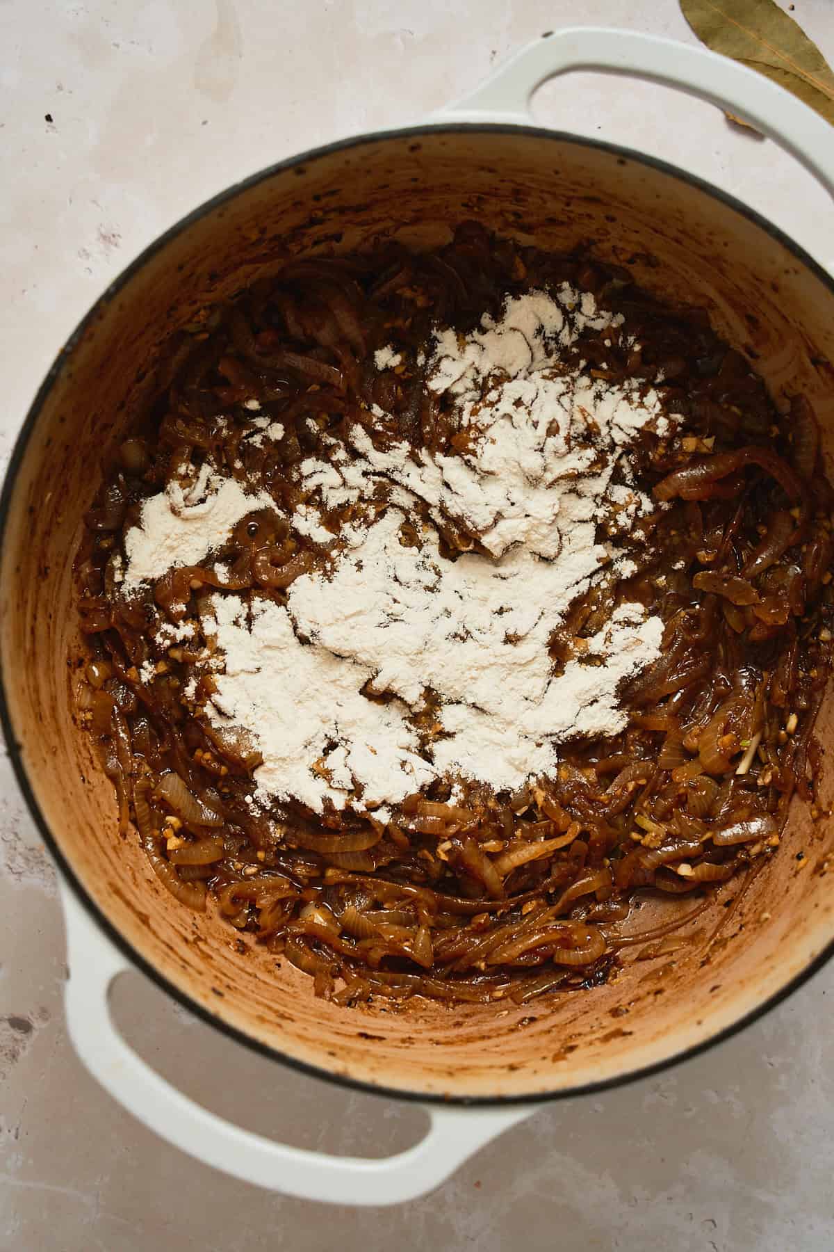 Flour added to a pot of onions being caramelized.