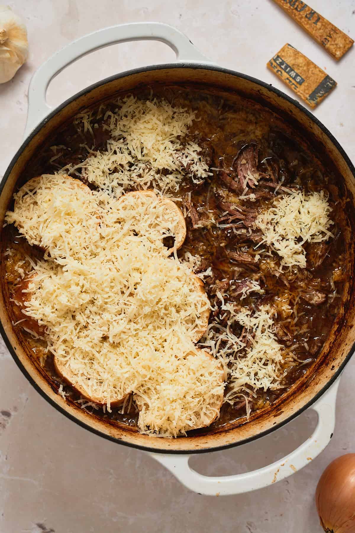 Shredded beef added to braising liquid then topped with baguette slices and gruyere cheese.