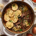 French onion pot roast topped with cheesy toast in a Dutch oven.