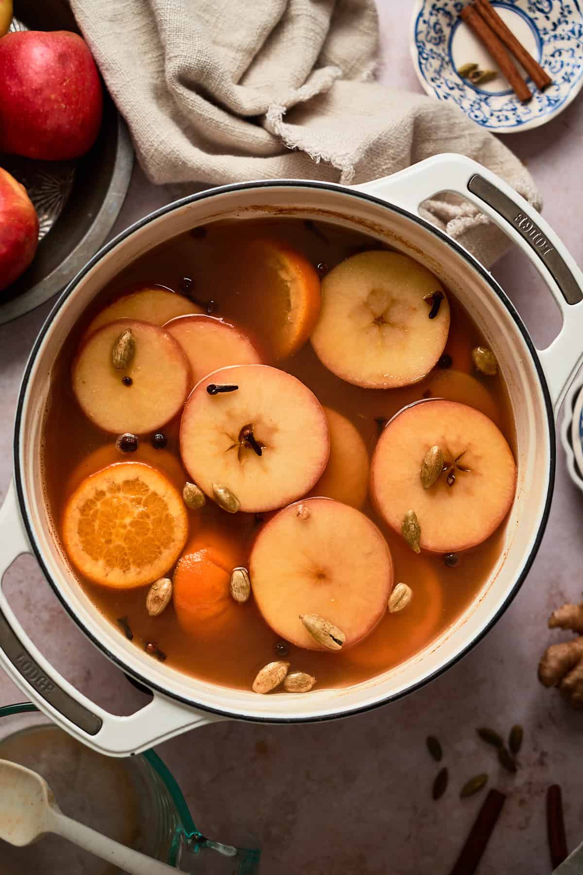 Fresh apple and orange slices soaking in a warm juice with whole spices.