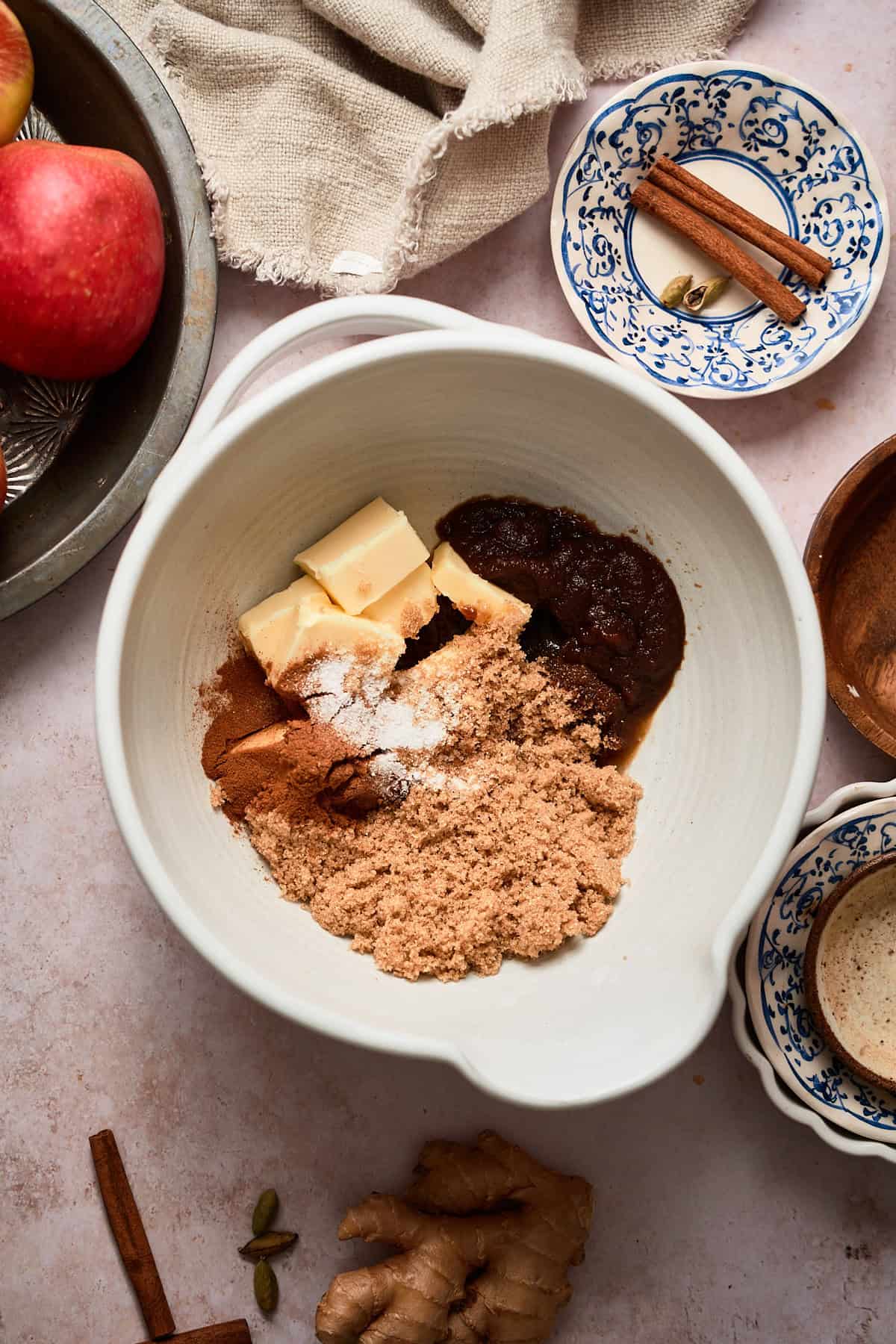 Brown sugar and butter with cinnamon, and other spices and butter in a mixing bowl, ready to be mixed.