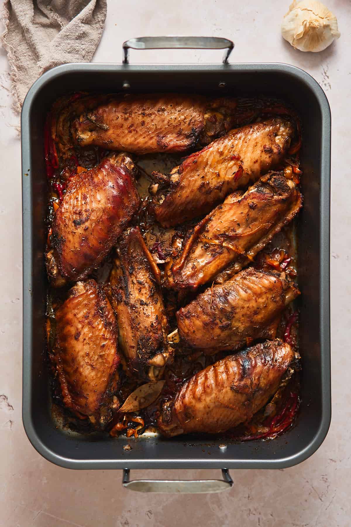 Roasted turkey wings turning a deep brown color in a roasting pan.