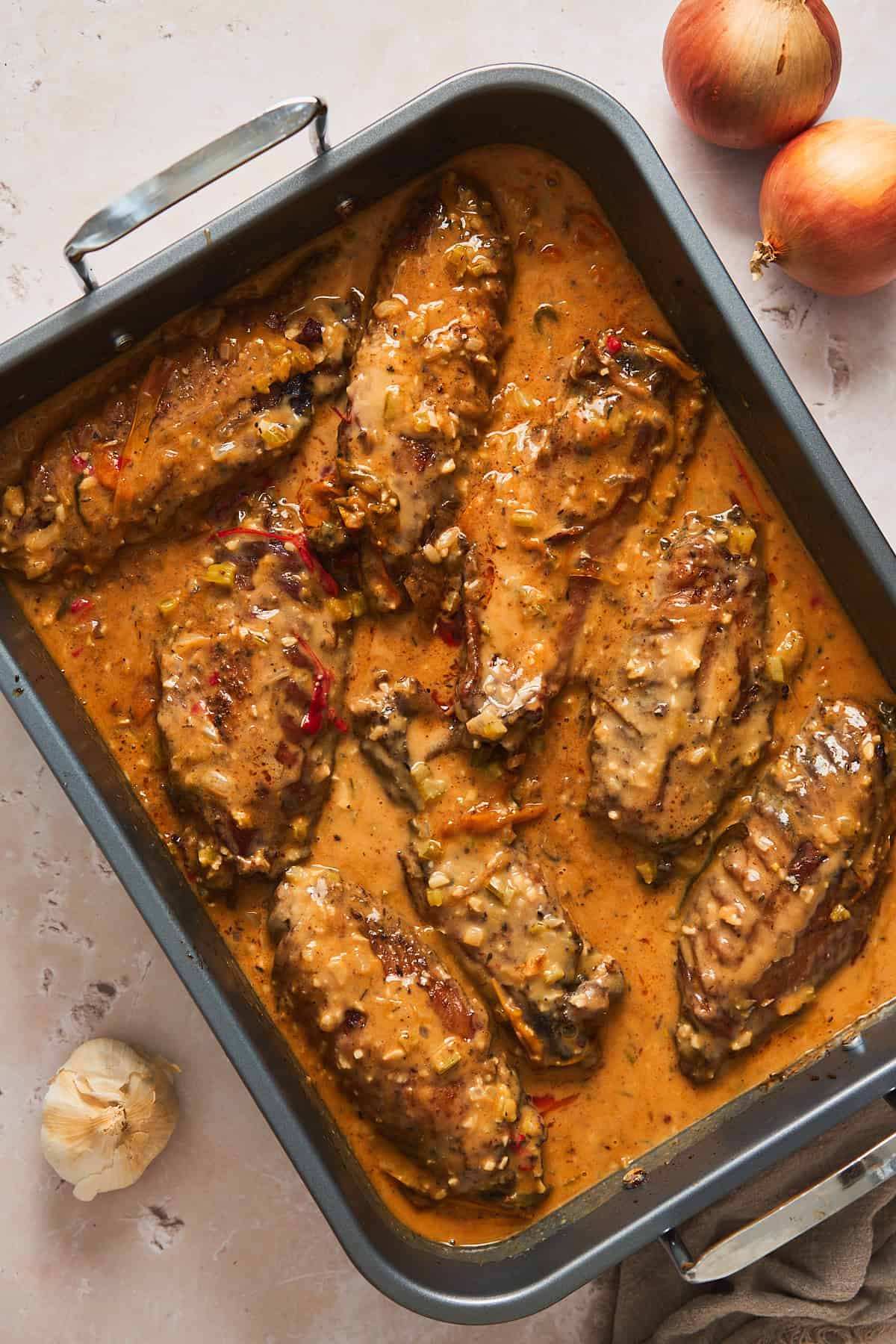 Turkey wings in a roasting pan covered in a silky smooth pan gravy getting ready to roast in the oven.