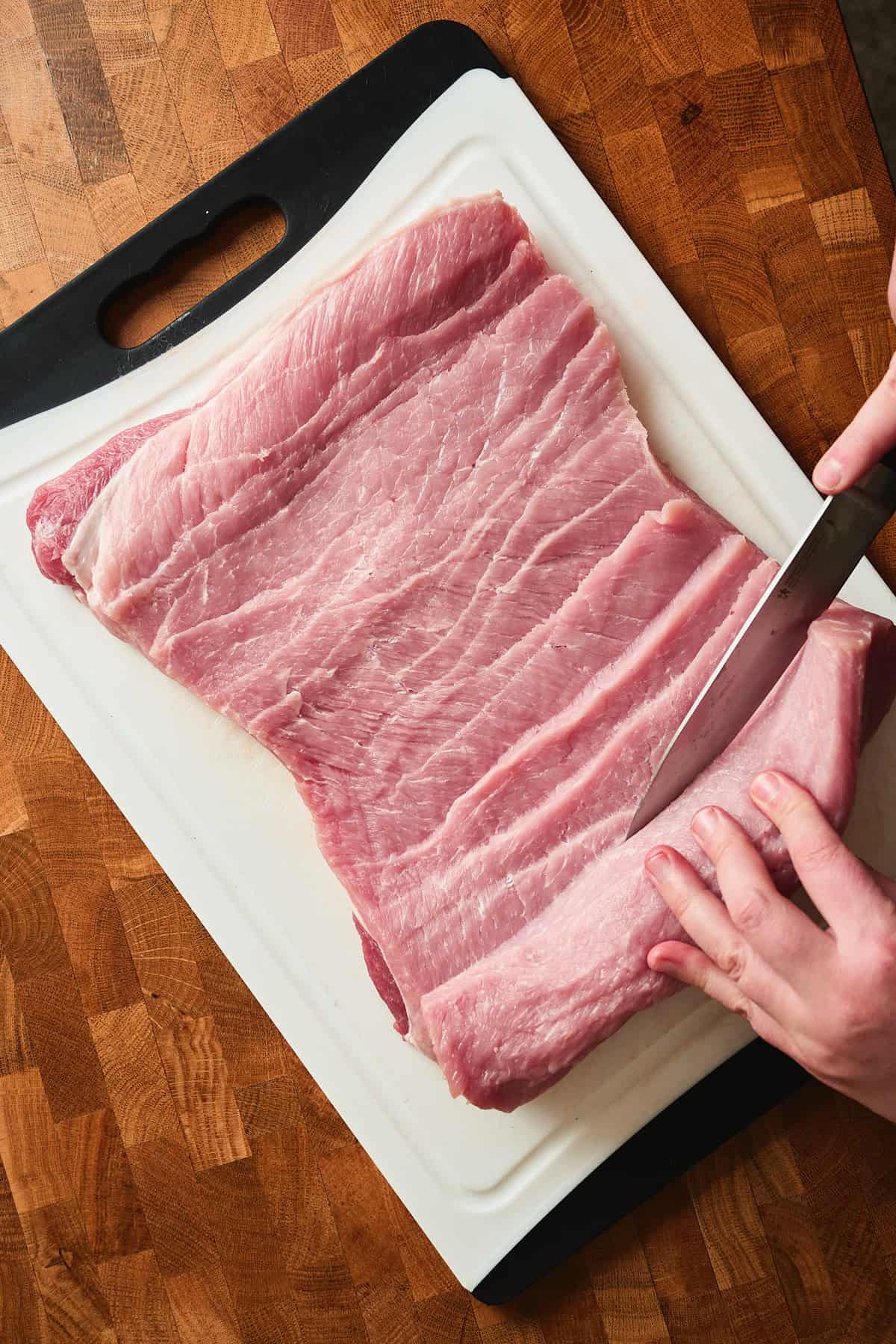 Pork loin being cut and rolled out very thin.