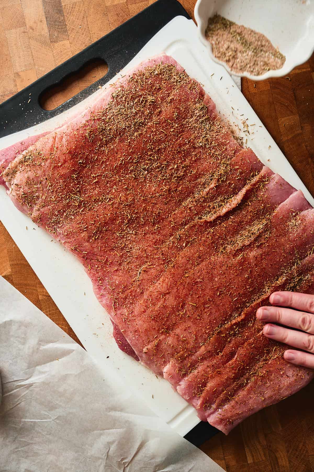 Well seasoned pork that has been butterflied on a plastic cutting board.