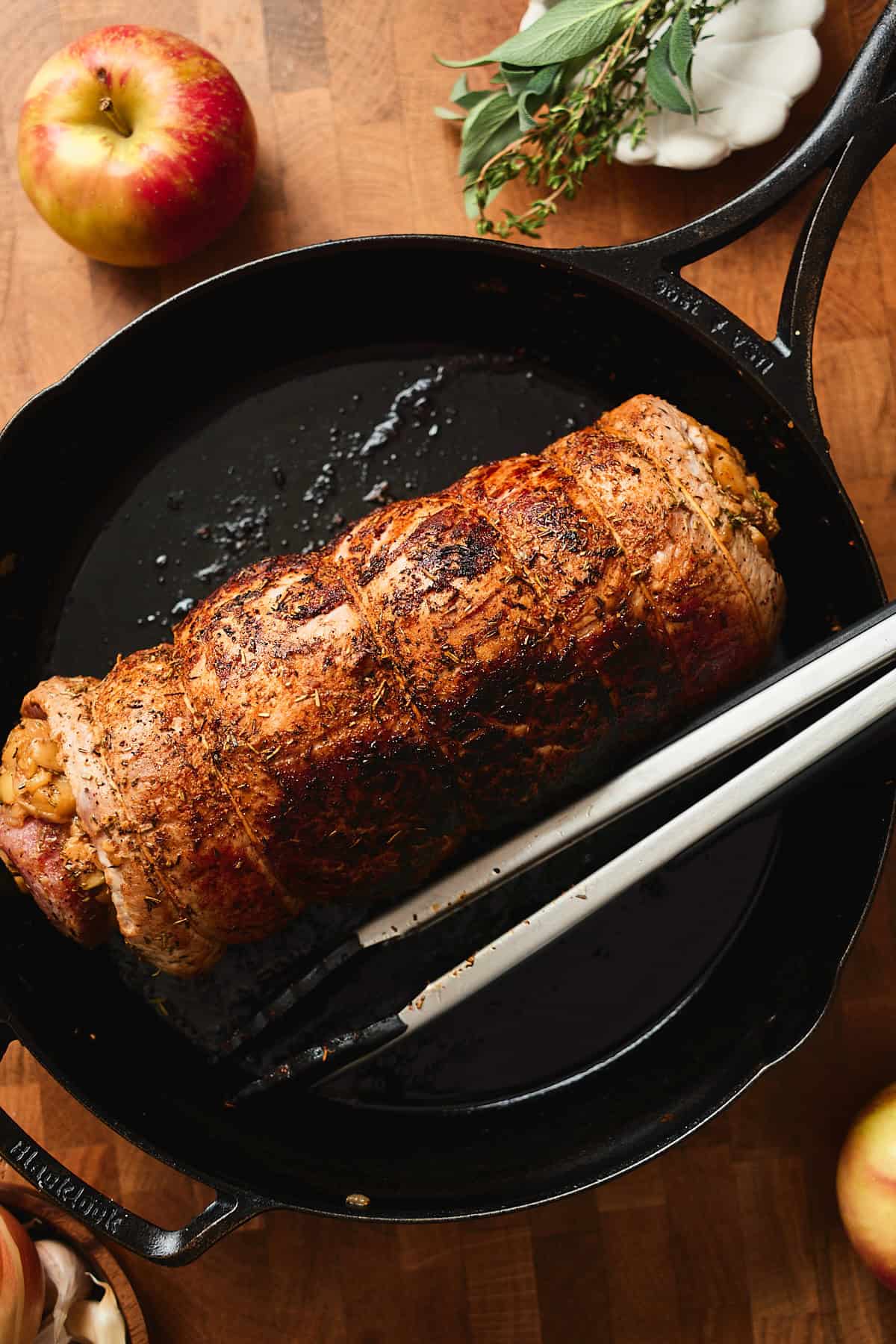 Pork loin roast getting seared until golden brown on all sides in a large skillet.